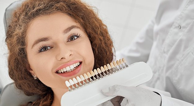 woman smiling while male dentist keeping teeth color range